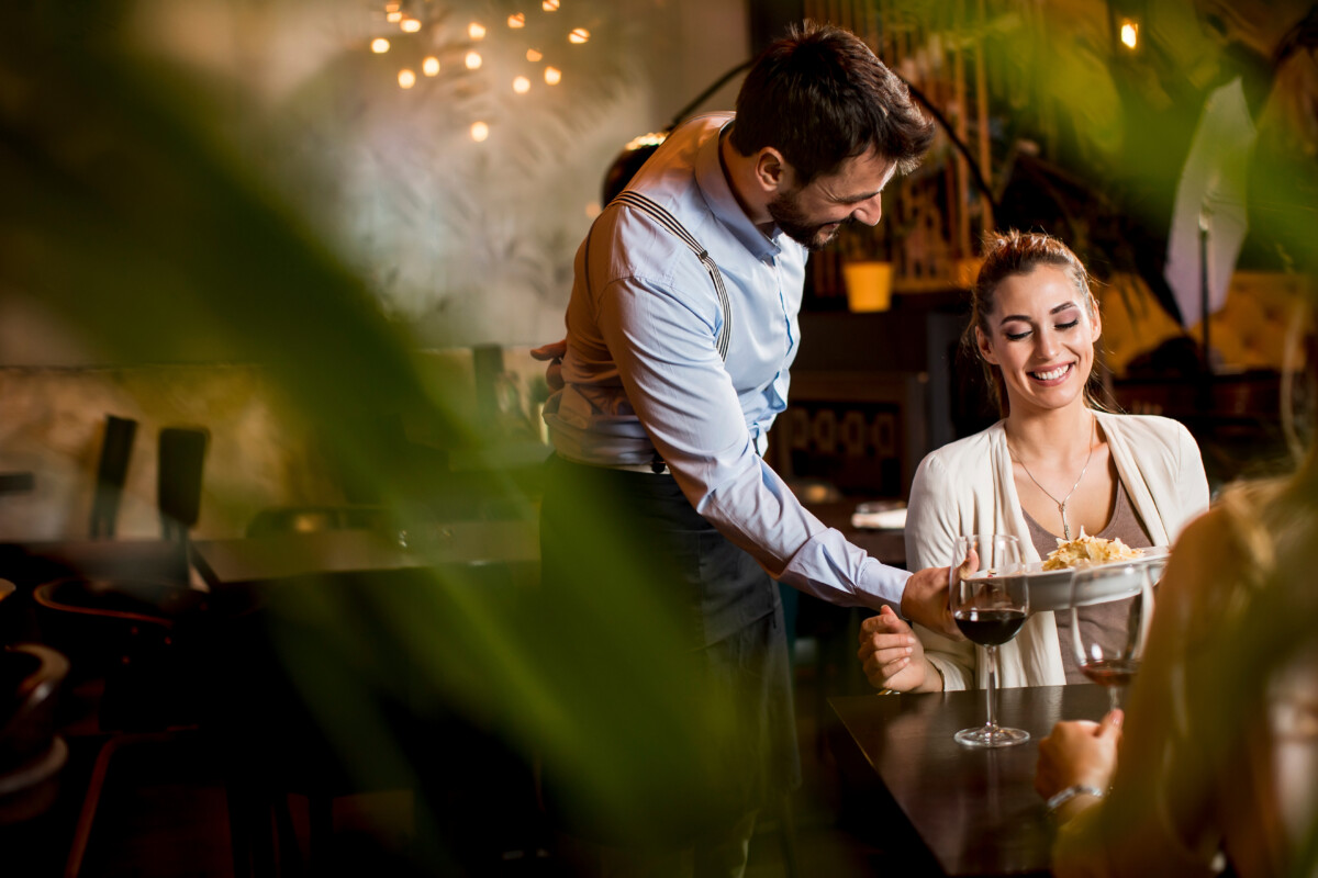 female at a restaurant with waiter serving