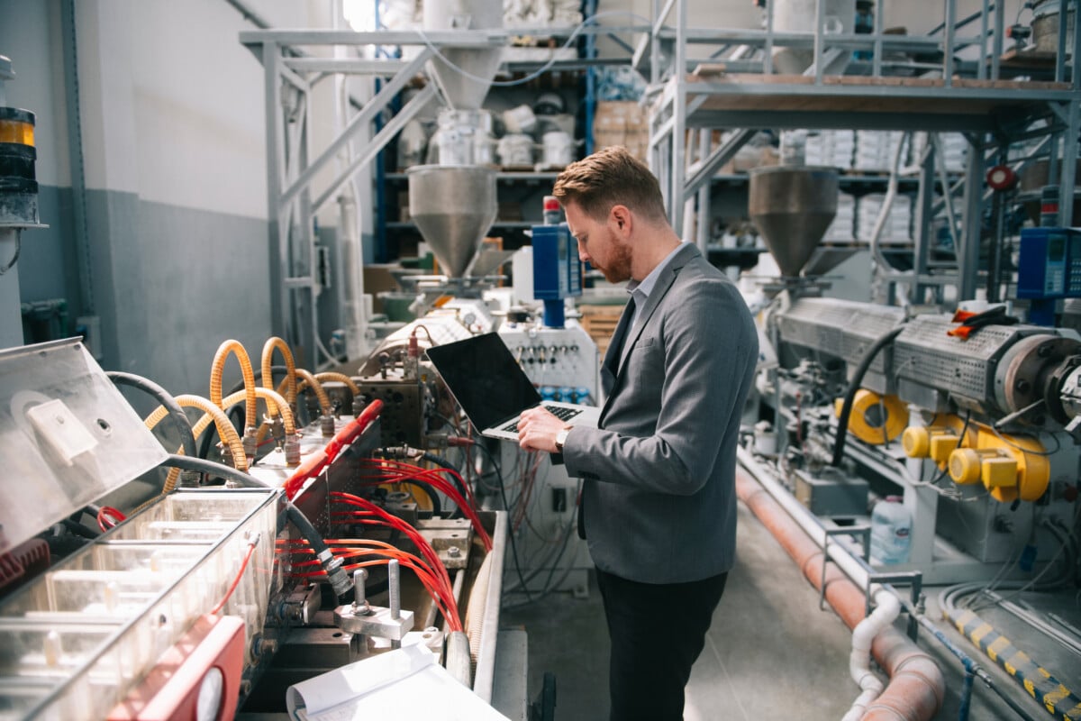 Manager checks machine using laptop