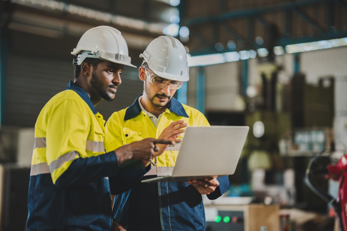 two colleagues looking at a laptop in factory