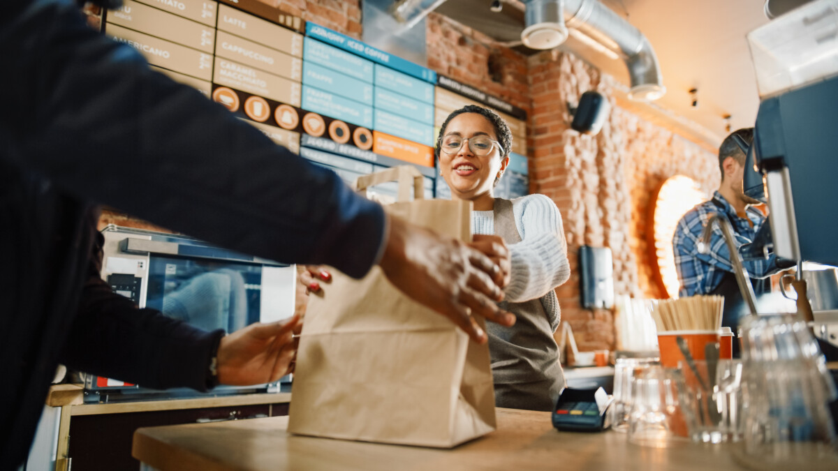 restaurant employee handing over a takeout to customer