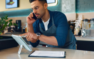 coffee shop manager using phone and tablet for stock check