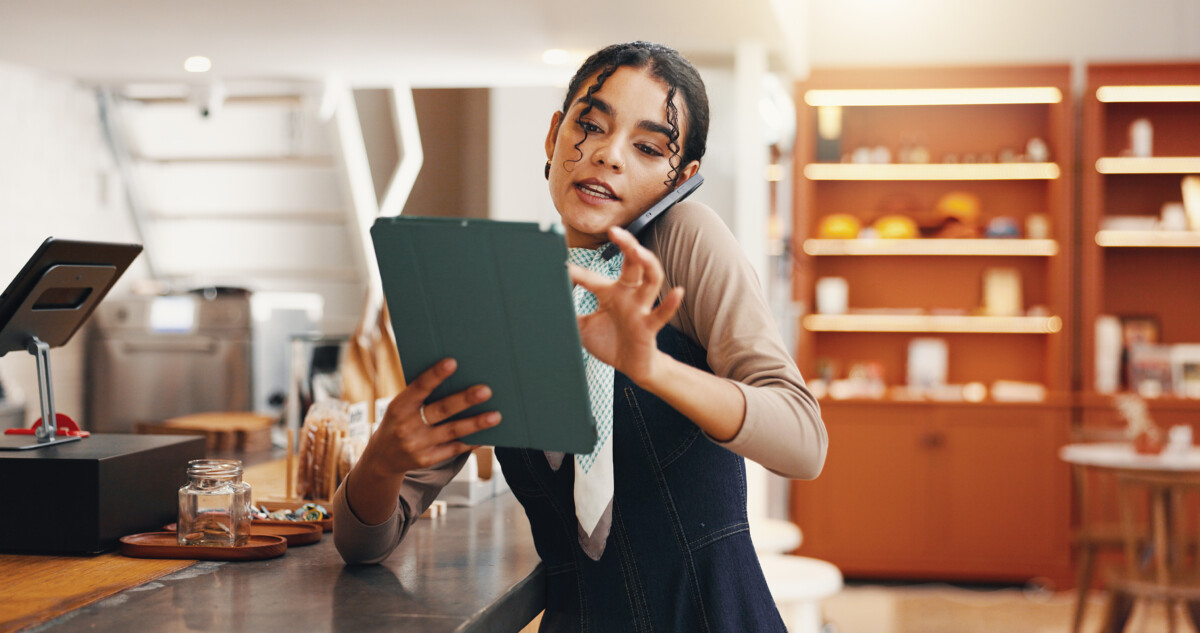woman in cafe using phone and tablet for inventory checklist