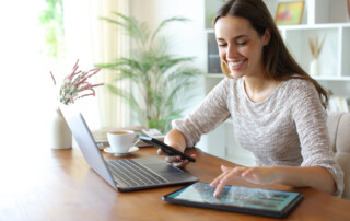 woman using multiple devices at dining table