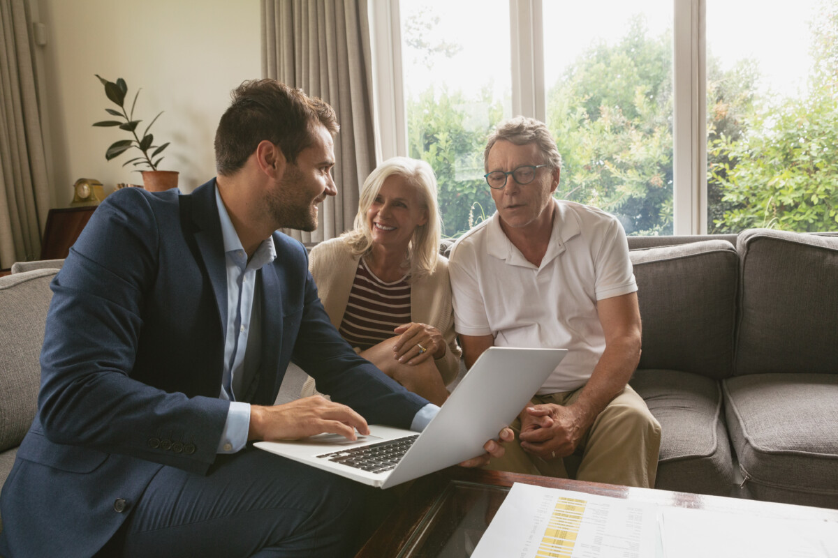 senior couple discussing with real estate agent over laptop