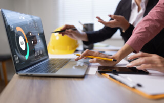 business colleagues collaborating on project planning using a laptop with advanced digital dashboard interface