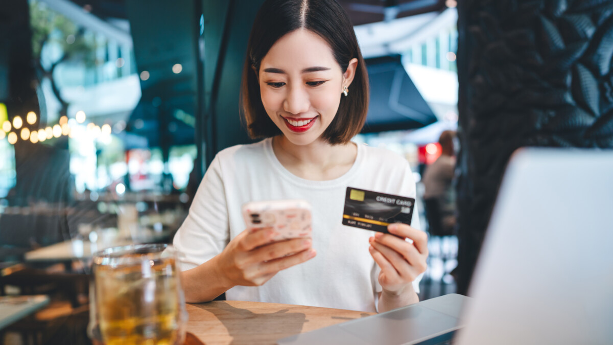 woman using credit card with internet banking mobile app sitting at cafe