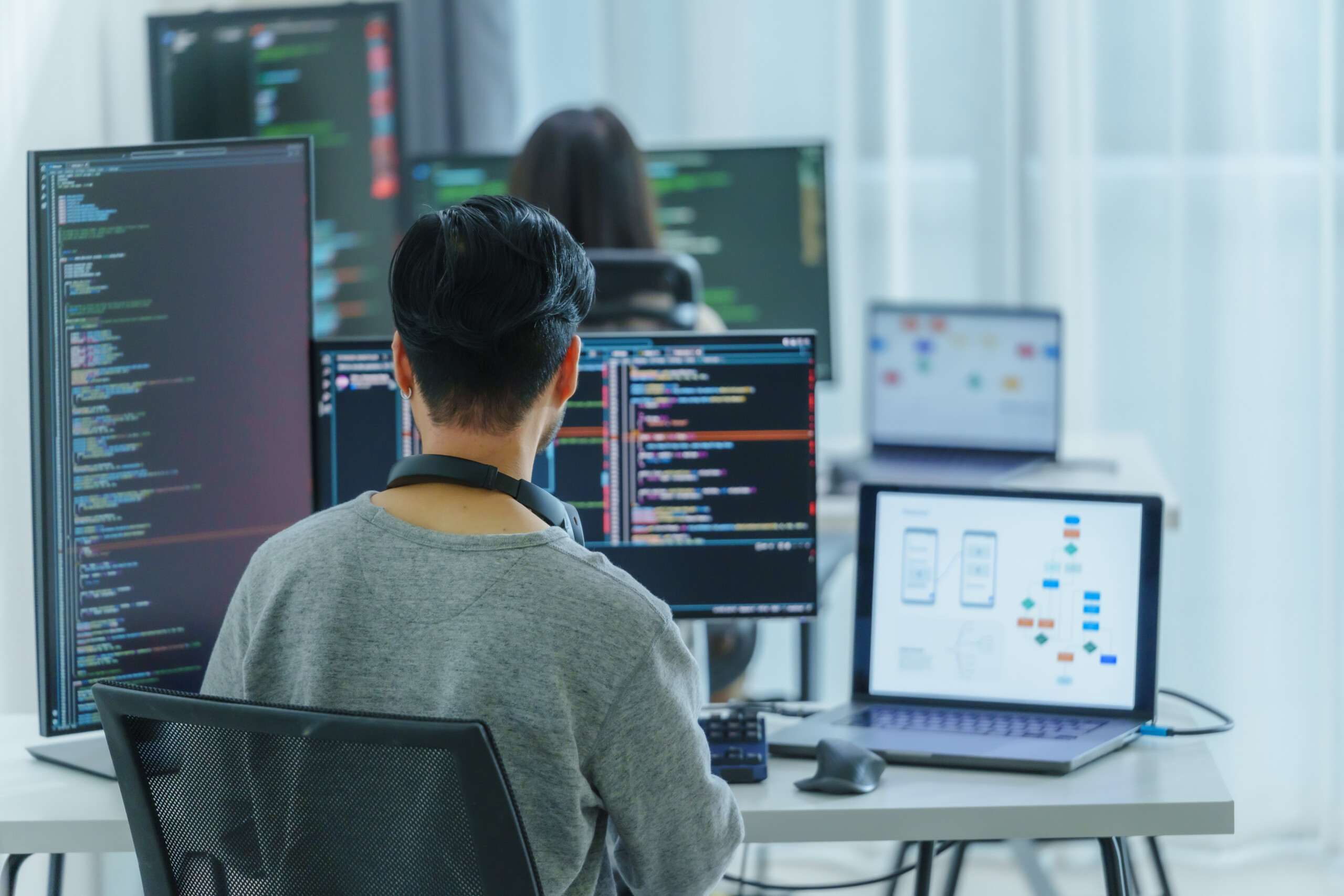 software developers working on multiple screens displaying code and application diagrams in a modern office
