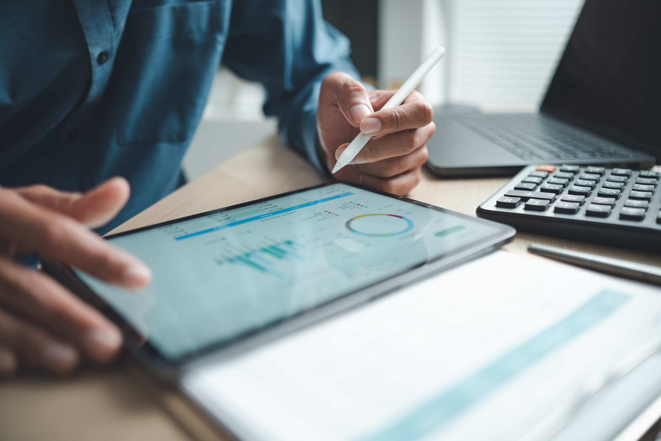 Business professional analyzing data on digital tablet dashboard with calculator and laptop