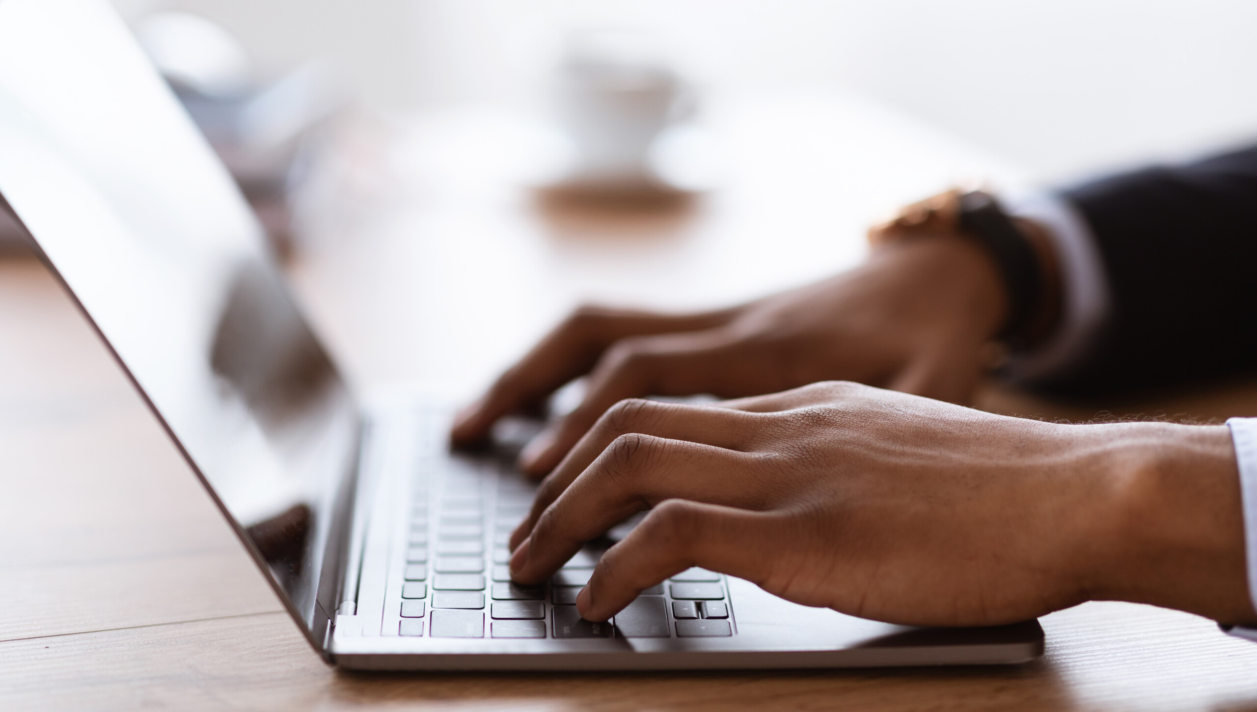 Male hands typing on laptop keyboard cropped