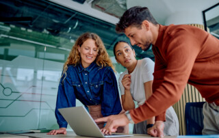 business team collaborating and discussing project strategy pointing at laptop screen in a modern office