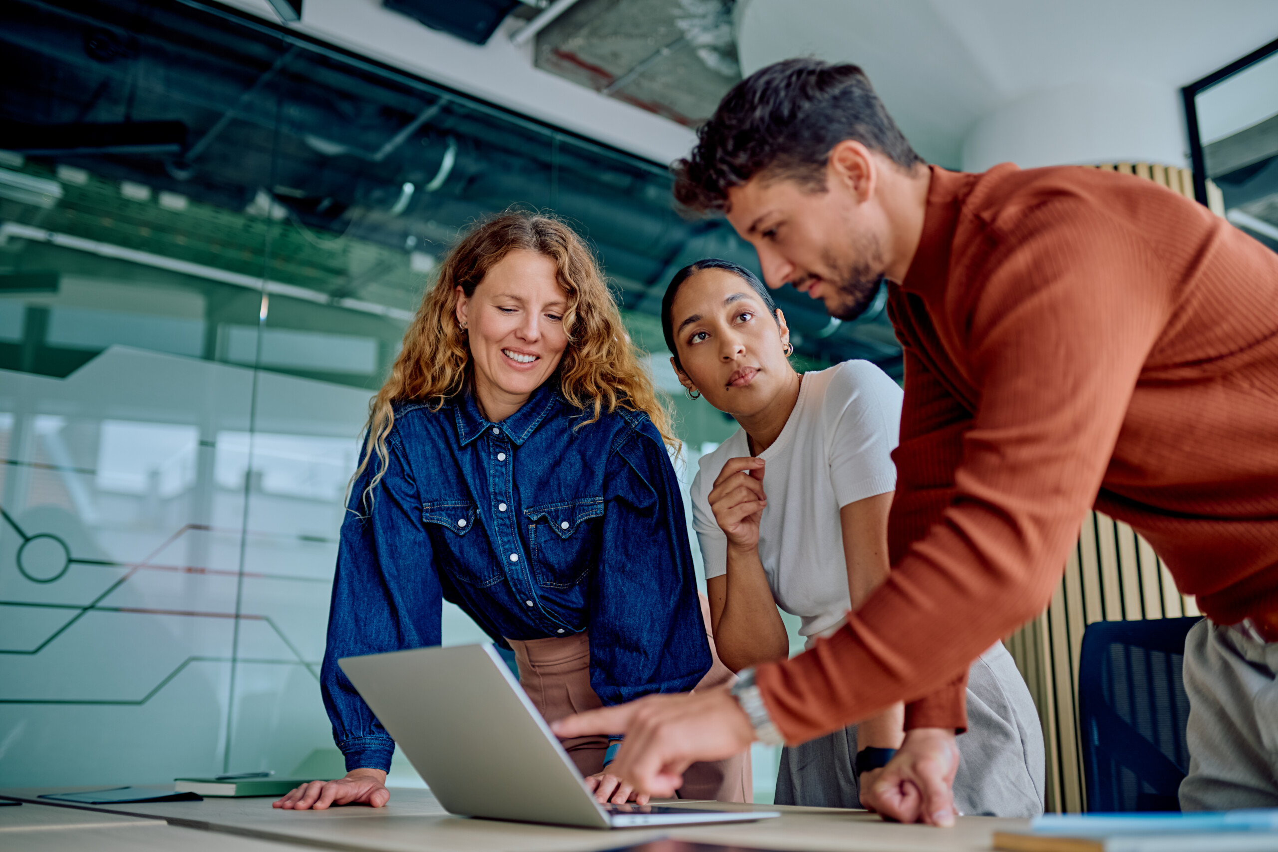 business team collaborating and discussing project strategy pointing at laptop screen in a modern office