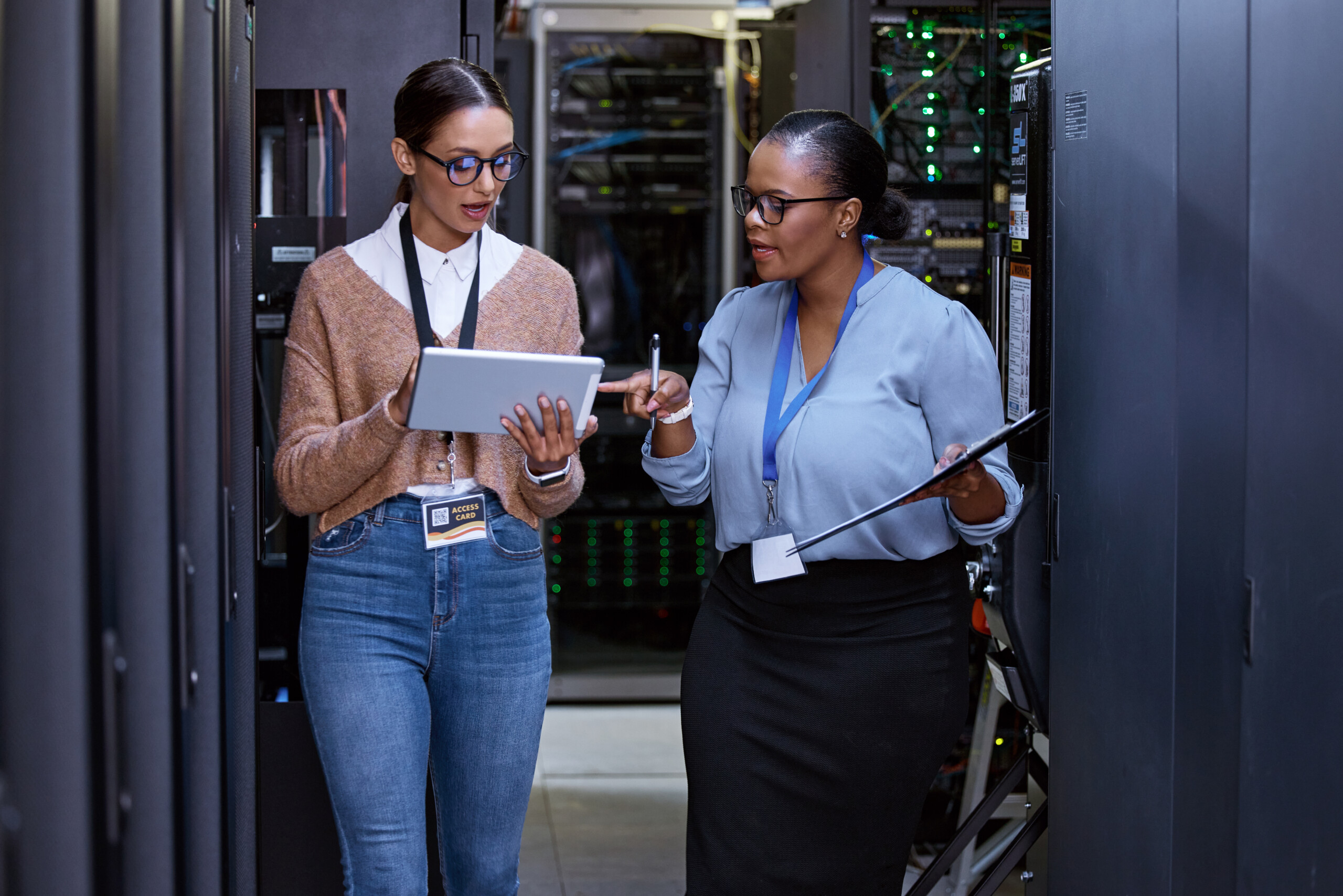 Teamwork, technician and female programmers speaking with technology for coding, hardware and system