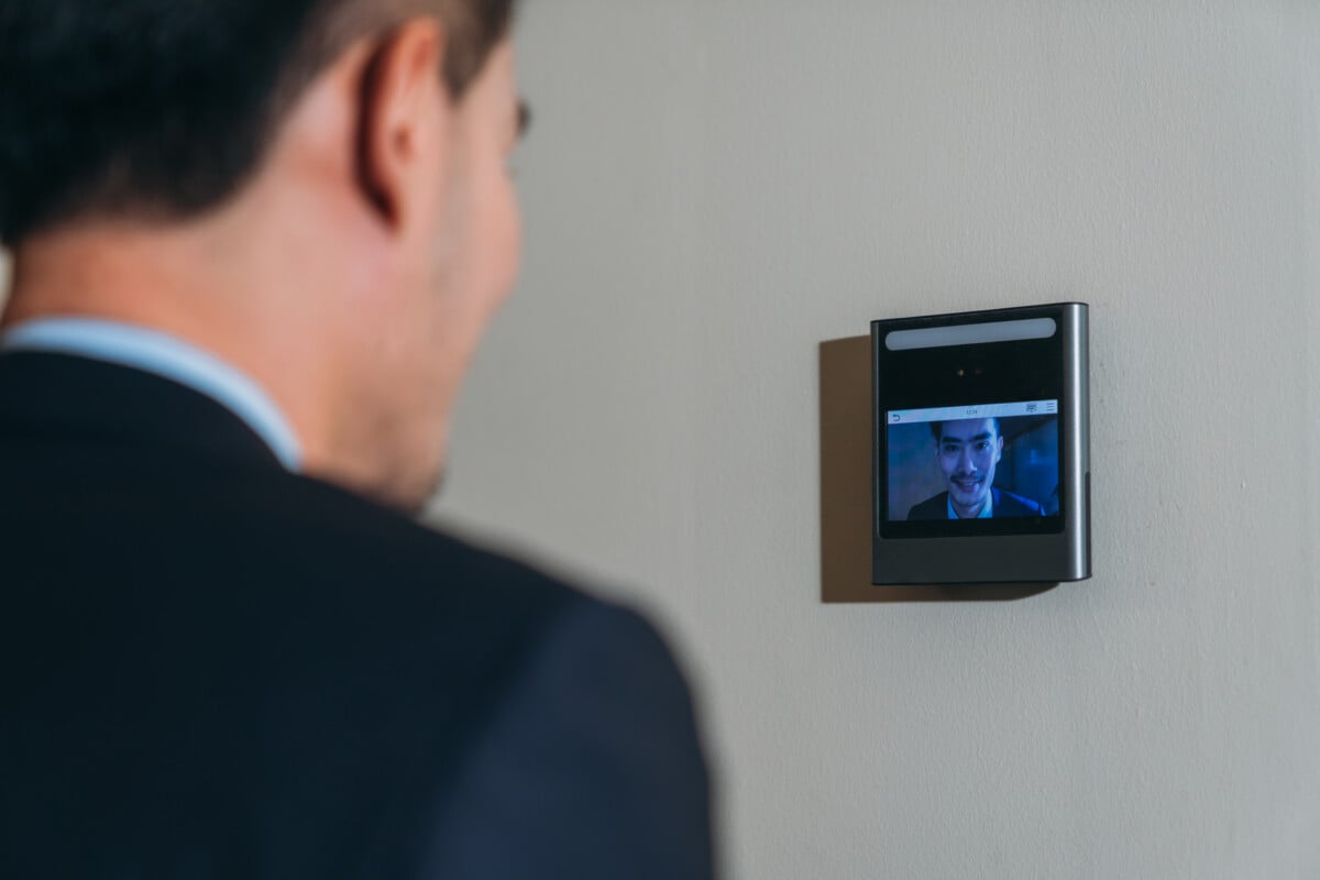 A face scanner being used by a man to open a door at an office building. Control device for Security system. Device to control a security system.